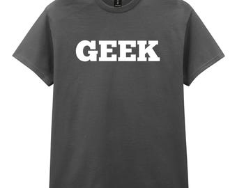 Puede incluir: Camiseta gris oscuro con la palabra "GEEK" impresa en letras mayúsculas blancas y en negrita en el pecho. La camiseta tiene mangas cortas y cuello redondo.