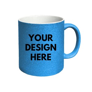 Puede incluir: Una taza azul brillante con purpurina, interior blanco y asa curva. La parte frontal de la taza presenta el texto negro "YOUR DESIGN HERE" impreso en una fuente negrita sin remates, centrado sobre la superficie azul brillante del recipiente.