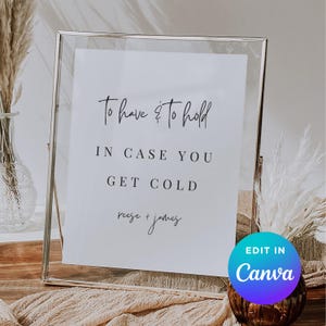 Könnte beinhalten: Ein gerahmtes weißes Schild mit dem Text "To have & to hold, IN CASE YOU GET COLD, reese + james." Das Schild befindet sich in einem transparenten Glasrahmen. Eine blau-violette Grafik "Edit in Canva" befindet sich unten rechts.
