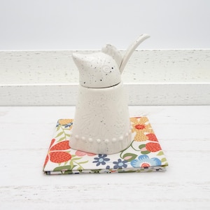 May include: A trio of ceramic mugs with a speckled, matte finish in cream, light grey, and dark grey. The mugs have a simple, minimalist design, suitable for coffee or tea.