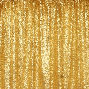 May include: Gold sequin backdrop for photography or event decor. The backdrop is made of a shimmering gold fabric with a vertical pattern.