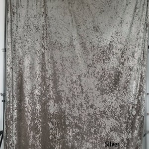 May include: A silver crushed velvet backdrop for photography. The backdrop is textured and has a subtle shimmer. The word "Silver" is printed in black at the bottom right corner.