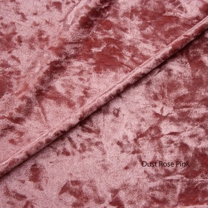May include: Close-up of a soft, dusty rose pink velvet fabric with a subtle marbled pattern. The fabric is folded in half, creating a diagonal line across the image. The text "Dust Rose Pink" is visible in the lower right corner.