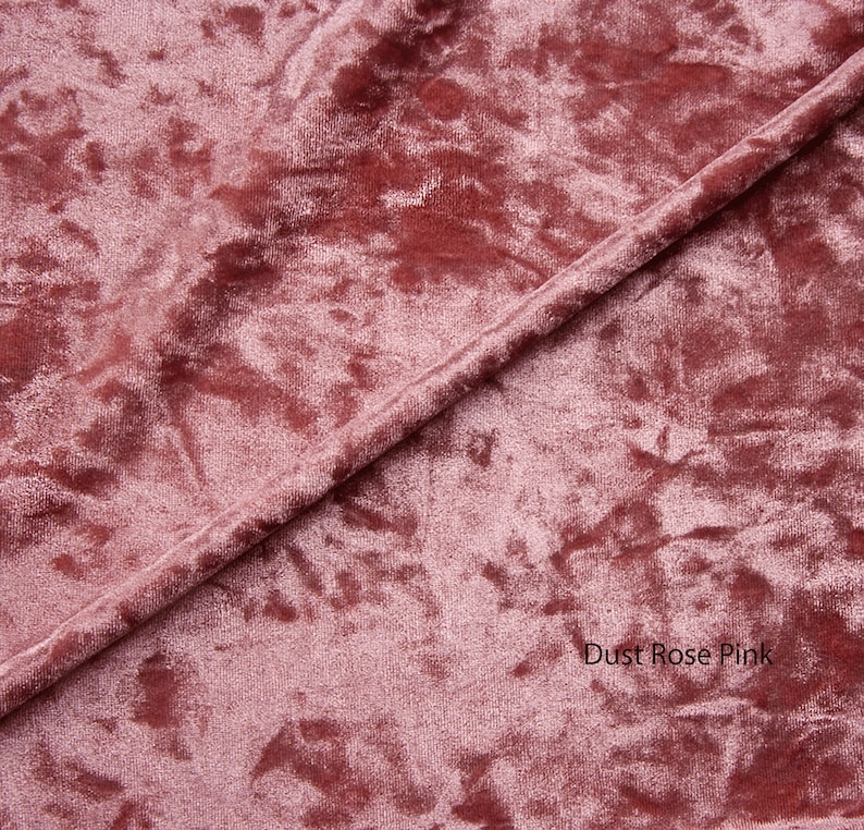 May include: Close-up of a soft, dusty rose pink velvet fabric with a subtle marbled pattern. The fabric is folded in half, creating a diagonal line across the image. The text "Dust Rose Pink" is visible in the lower right corner.