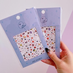 May include: Two packs of nail art stickers with Halloween designs, including ghosts and pumpkins. The stickers are displayed in light blue packaging with a cartoon ghost logo and the text "Miss Goldenweek" and "@miss_goldenweek".