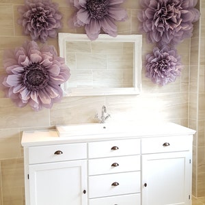 Puede incluir: Mueble de ba&ntilde;o blanco con cuatro cajones y una puerta de armario. El mueble tiene una encimera blanca y un grifo cromado. La pared detr&aacute;s del mueble est&aacute; alicatada y decorada con grandes flores de papel morado.