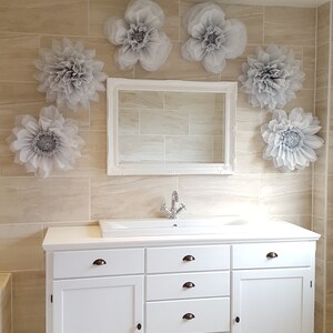 May include: White bathroom vanity with a white porcelain sink and chrome faucet. The vanity has five drawers and two doors. The wall behind the vanity is tiled and decorated with gray paper flowers.
