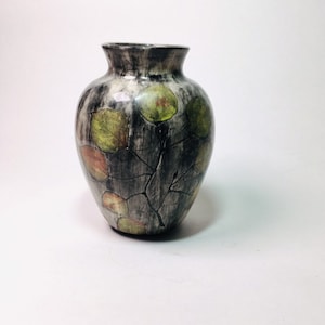 May include: A small, gray ceramic vase with a crackled glaze and a design of green and brown leaves.