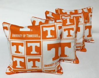 May include: Set of five orange and white bean bags with the University of Tennessee logo and the letter "T" repeated on each bag.
