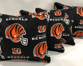 May include: Set of five black bean bags with a repeating pattern of orange and black Cincinnati Bengals logos, including the team's helmet and the number 13.