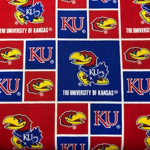 May include: Fabric with a repeating pattern of red and blue squares. Each square features the letters "KU", the University of Kansas Jayhawk mascot, and the words "THE UNIVERSITY OF KANSAS".