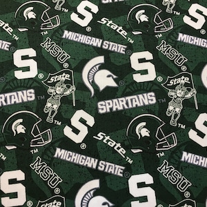 May include: Green and white patterned fabric featuring the Michigan State Spartans logo, helmets, and the text "Michigan State", "MSU", and "Spartans". The design is repeated across the fabric.