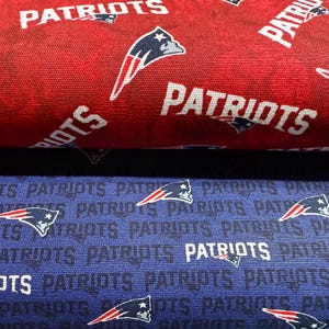 May include: Two rolls of fabric, one red and one blue, featuring the word "PATRIOTS" in white and the team logo. The red fabric has a gradient effect, while the blue fabric has a repeating pattern of the team name and logo.