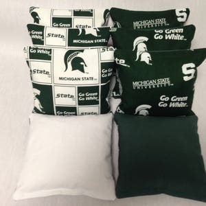May include: Set of bean bags with a green and white design featuring the Michigan State University logo and the text "Go Green Go White".