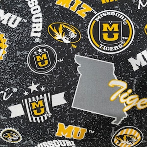 May include: Black and gold fabric with a repeated pattern of the Missouri Tigers logo, the words "Missouri Tigers", and the letters "MU".
