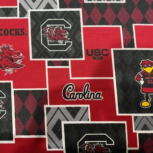 May include: Red and black fabric with a patchwork design featuring the University of South Carolina Gamecocks logo, mascot, and the words "Gamecocks", "USC", and "Carolina".
