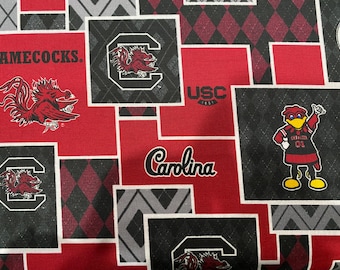 May include: Red and black fabric with a patchwork design featuring the University of South Carolina Gamecocks logo, mascot, and the words "Gamecocks", "USC", and "Carolina".