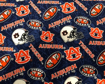 May include: A blue fabric with a repeating pattern of orange and white Auburn University logos. The logos include the letters "AU", a tiger head, and the words "Auburn Tigers".
