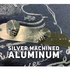 May include: Silver machined aluminium guitar control plate with two knobs and the text "Lucky Dog" engraved on the surface.