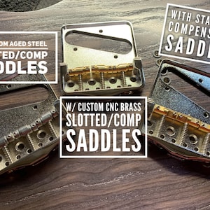 Op de afbeelding: Drie gitaarbrugzadels met verschillende afwerkingen. Het bovenste zadel is gelabeld "With Standard Compensated Saddles". Het middelste zadel is gelabeld "W/ Custom Aged Steel Slotted/Comp Saddles". Het onderste zadel is gelabeld "W/ Custom CNC Brass Slotted/Comp Saddles".
