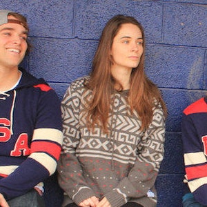 May include: Three people wearing sweaters with the word "USA" on them. The person on the left is wearing a navy blue sweater with white and red stripes on the sleeves. The person in the middle is wearing a gray sweater with a geometric pattern. The person on the right is wearing a navy blue sweater with red and white stripes on the sleeves.