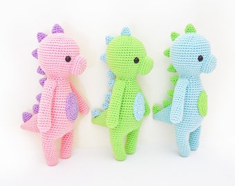 May include: Three crocheted dinosaur toys in pink, green, and blue. Each dinosaur has a small, round, purple, green, or blue spot on its back.