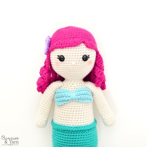 Op de afbeelding: Een gehaakte zeemeerminpop met roze haar, een blauwe top en een groene staart.