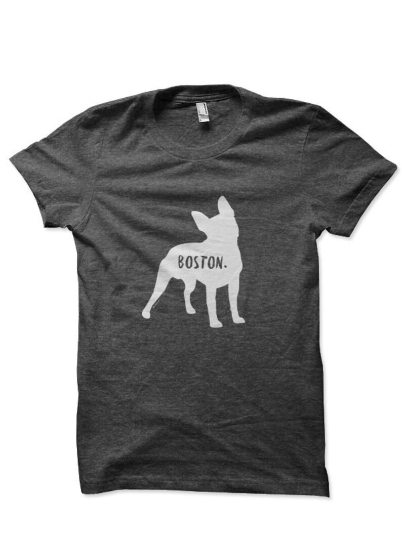 May include: Dark gray t-shirt featuring a white silhouette of a dog with the word "BOSTON" printed below. The shirt has short sleeves and a crew neck. The design is simple and graphic.