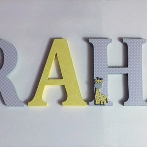 May include: Wooden letters spelling the name "GRAHAM" in yellow and grey with a small giraffe figurine on the "H".