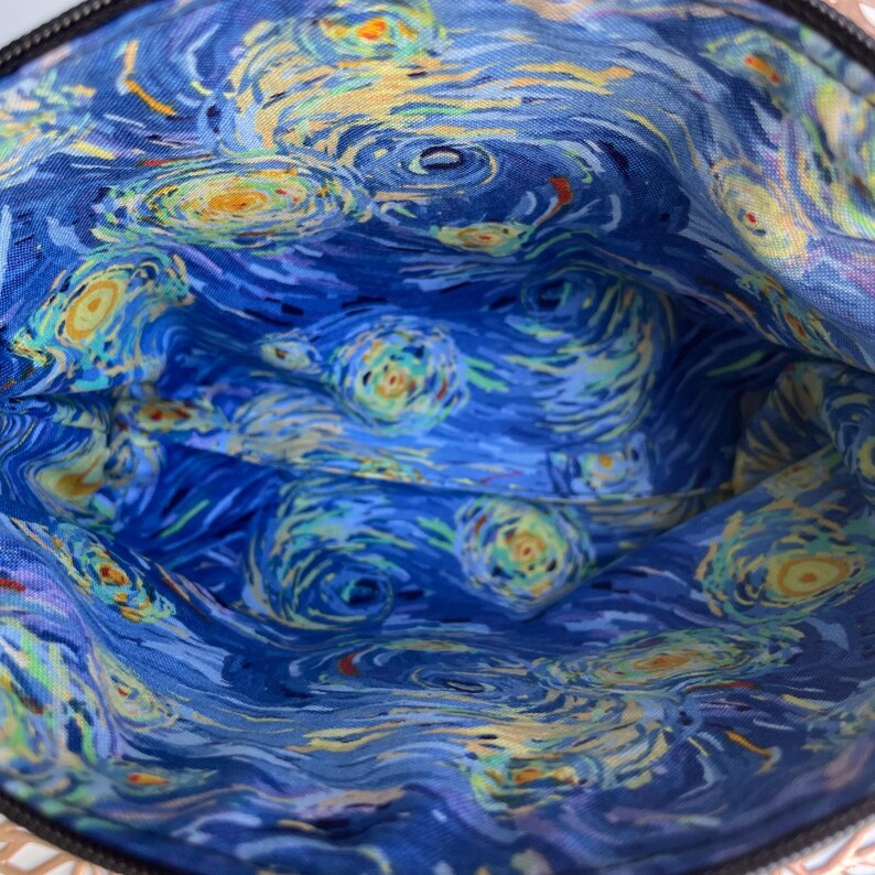 Puede incluir: El interior de una bolsa o estuche est&aacute; forrado con una tela azul con un patr&oacute;n de remolino que recuerda a la pintura "La noche estrellada" de Vincent van Gogh.
