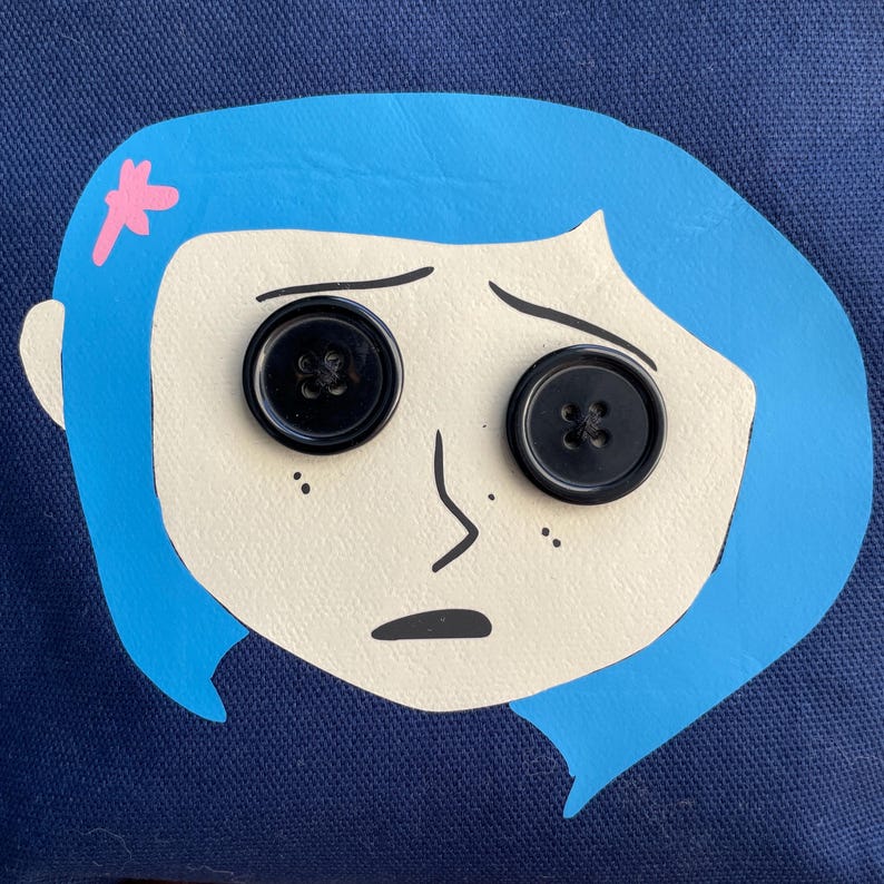 Puede incluir: Una ilustraci&oacute;n azul y blanca de una ni&ntilde;a con cabello azul y ojos negros en forma de botones. La ni&ntilde;a tiene una flor rosa en la cabeza y una expresi&oacute;n triste.
