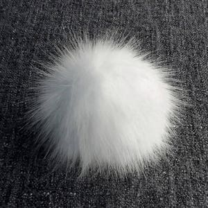 May include: A fluffy white pom pom, perfect for adding a touch of whimsy to hats, scarves, or other crafts.