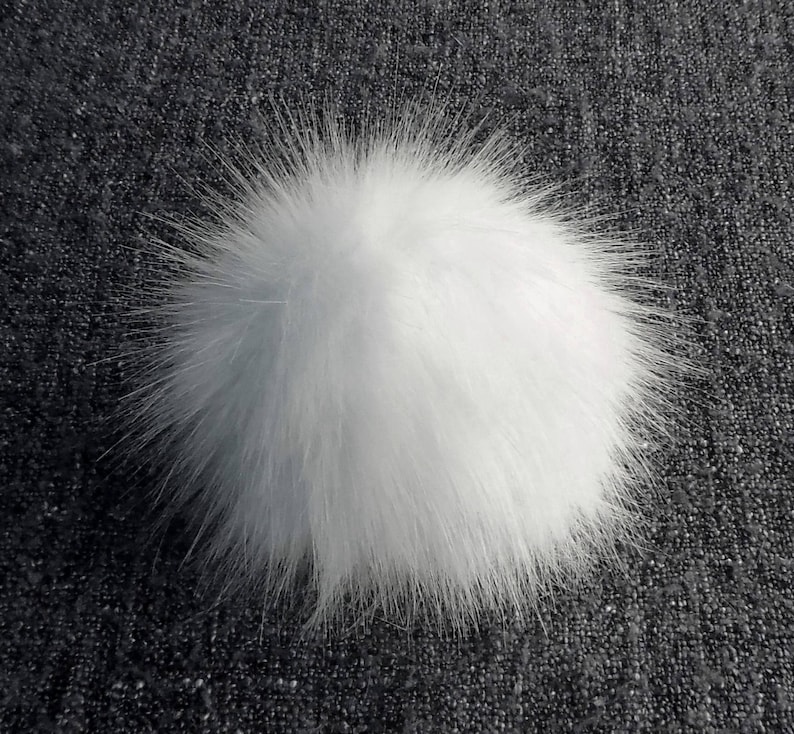 May include: A fluffy white pom pom, perfect for adding a touch of whimsy to hats, scarves, or other crafts.
