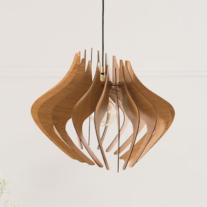 May include: A pendant light fixture featuring a series of curved, light brown wooden slats arranged in a symmetrical, organic shape. The structure hangs from a thin black cord and contains a single exposed light bulb in the center.