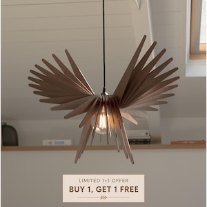 May include: A dark brown wooden pendant light fitting featuring multiple thin, radiating slats arranged in a wing-like shape around a central exposed Edison-style light bulb, suspended from a single black cord hanging from the ceiling.