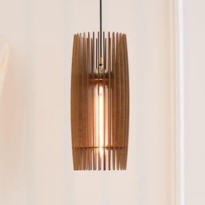 May include: A cylindrical pendant light fixture constructed from vertical brown wooden slats arranged in a cage-like pattern. The fixture features a central tubular Edison-style light bulb emitting a warm glow, suspended by a black cord.