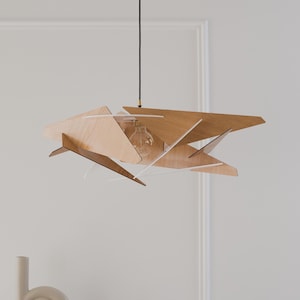 May include: A pendant light fitting featuring multiple angular, light-toned wooden panels arranged in a geometric, layered structure. The fitting is suspended by a thin black cord and includes a single exposed clear glass light bulb at the centre.