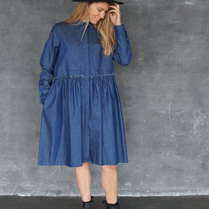 May include: A woman wearing a blue denim shirt dress with a black hat and black ankle boots.
