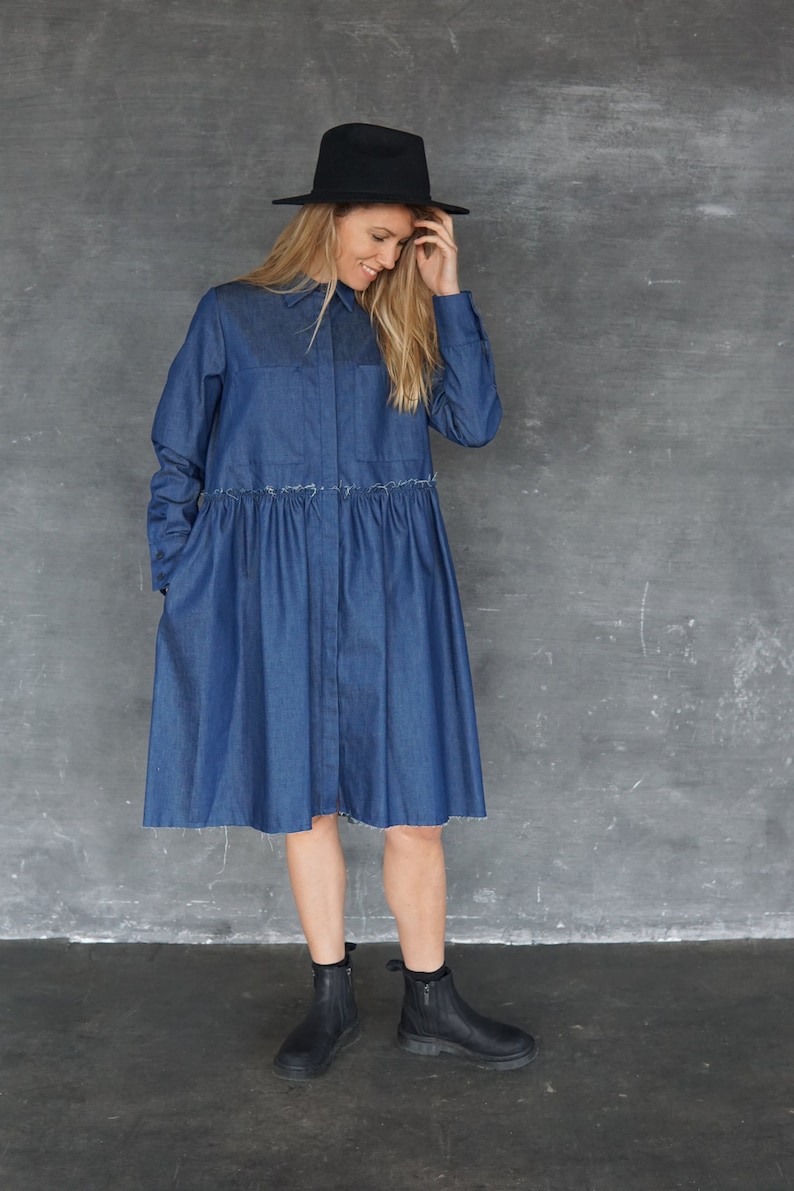 May include: A woman wearing a blue denim shirt dress with a black hat and black ankle boots.