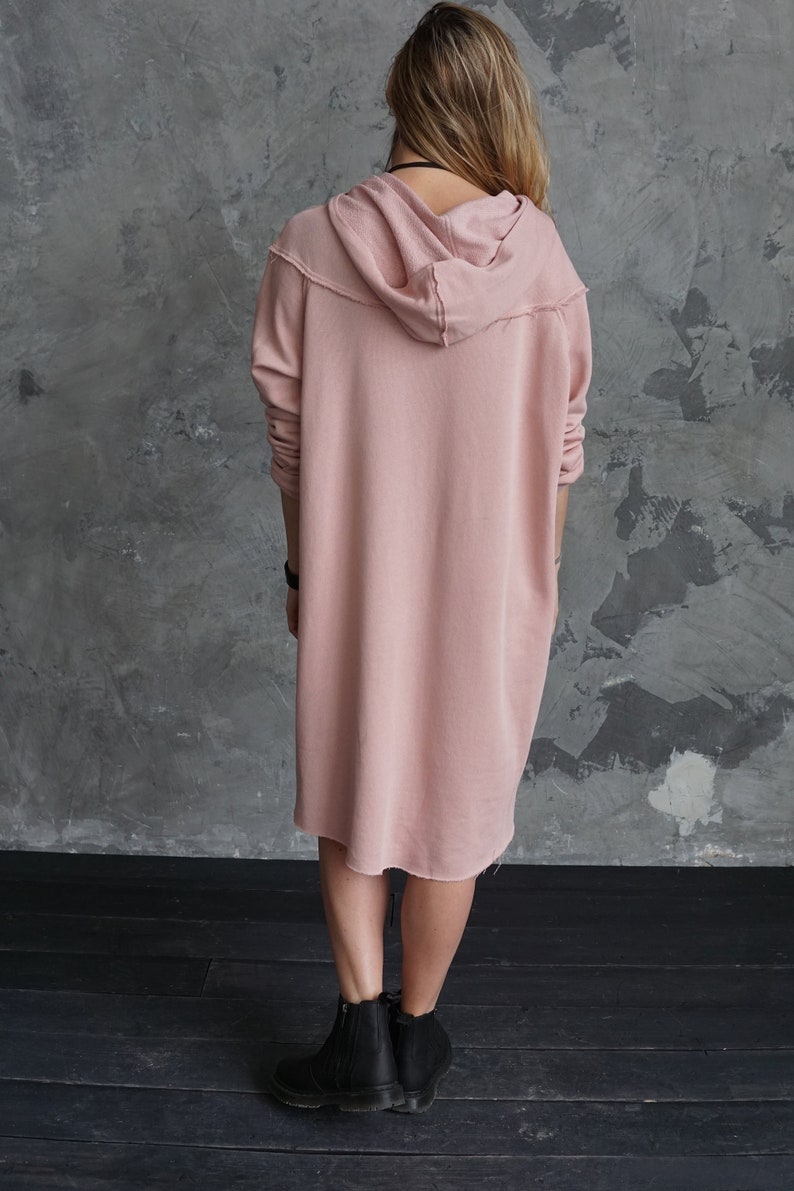 May include: A long, dusty rose hooded sweatshirt dress with a relaxed fit and a slightly frayed hem.