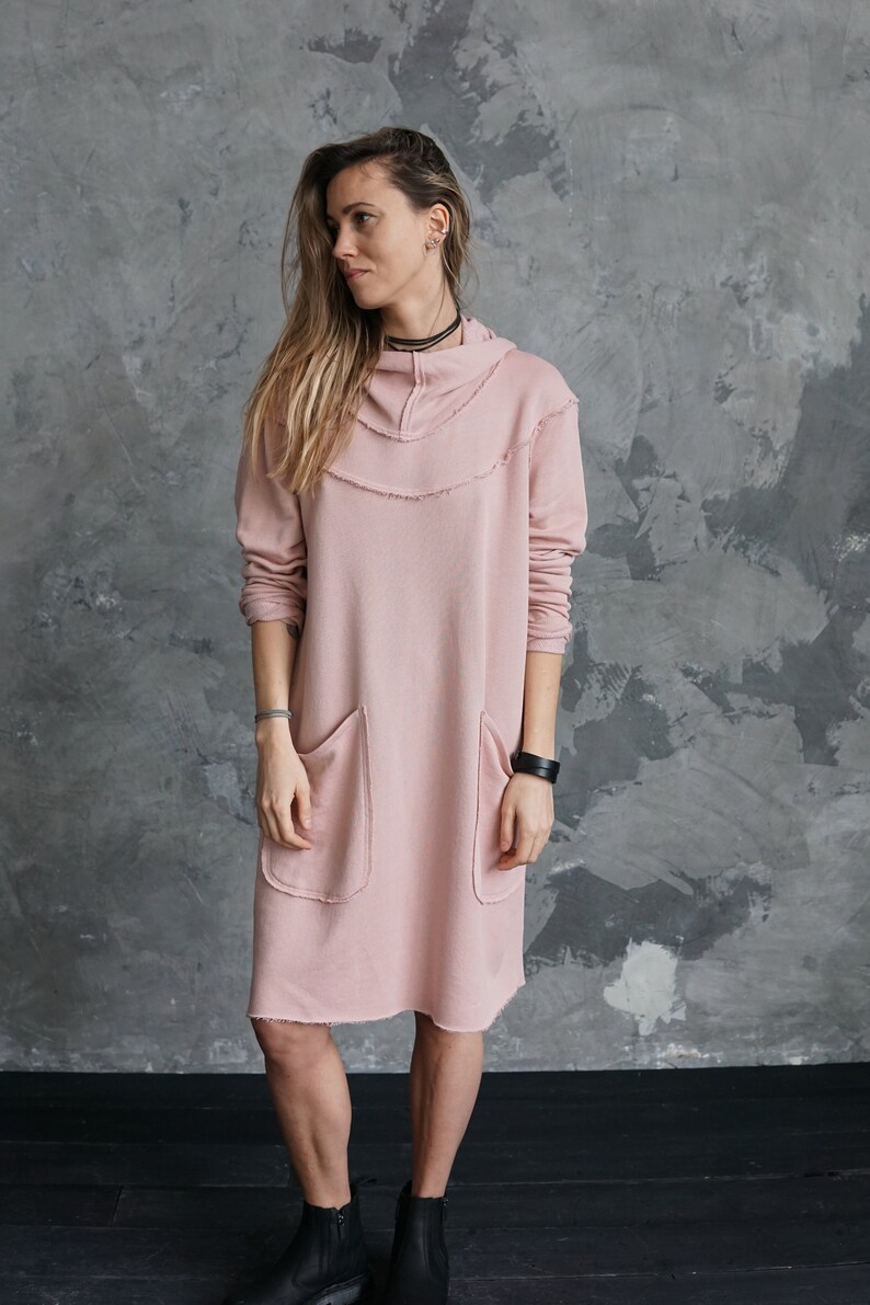May include: A pink, long-sleeved, hooded dress with two pockets and a frayed hem.