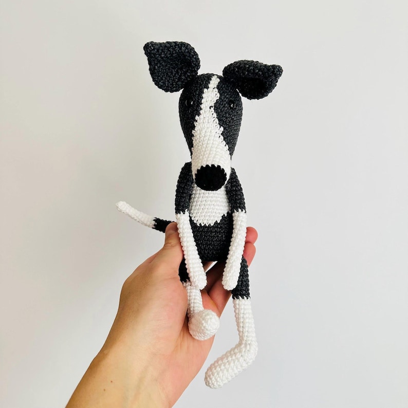 May include: A crocheted black and white dog toy with long legs and floppy ears.