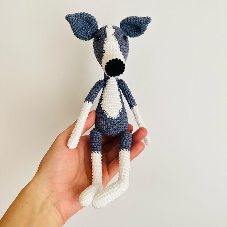 May include: A crocheted grey and white dog toy with black eyes and a black nose.