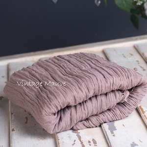 Peut inclure: Une toile de fond en tissu mauve vintage pliée pour la photographie. Le tissu a une texture froissée et est plié en trois.