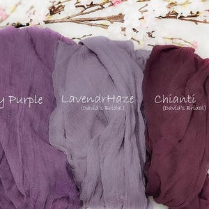 May include: Three pieces of crinkled fabric in shades of purple. The left piece is labeled Dusty Purple, the center piece is labeled LavendrHaze (David's Bridal), and the right piece is labeled Chianti (David's Bridal). The fabric has a sheer texture.
