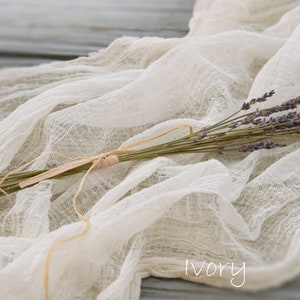 May include: A bunch of dried lavender tied with twine, resting on a white, sheer fabric with the word "ivory" written on it.