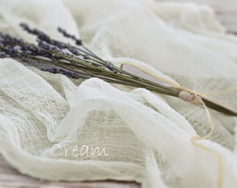 May include: A bunch of dried lavender tied with twine, resting on a cream-colored fabric background. The fabric has a delicate, open weave.