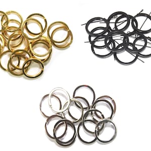 May include: Assortment of key rings in gold, silver, and black metal. The key rings are all circular and are arranged in three groups.