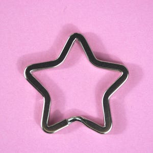 May include: A silver star-shaped key chain with a smooth, shiny finish.