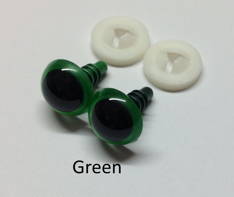 May include: Two green plastic safety eyes with black pupils and a metal shank. The eyes are accompanied by two white plastic washers.